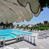 Piscina con lettini bianchi e grande ombrellone.