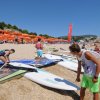 Spiaggia con windsurf e ombrelloni arancioni.