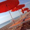 Ombrelloni arancioni su una spiaggia con lettini.