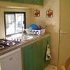 Cucina compatta con lavello e fornelli, accanto a un cestello per piatti.