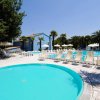 Piscina circondata da lettini e ombrelloni bianchi.