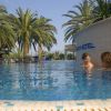 Due persone parlano in piscina circondate da palme.