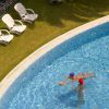 Due persone giocano a palla in piscina vista dall'alto.