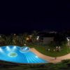 Piscina illuminata di notte vicino a un hotel.