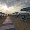 Spiaggia al tramonto con ombrelloni e sedie a sdraio.