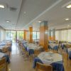 Ristorante elegante con tavoli apparecchiati, sedie e ampie finestre.