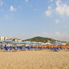 Una spiaggia con file di lettini e ombrelloni blu.