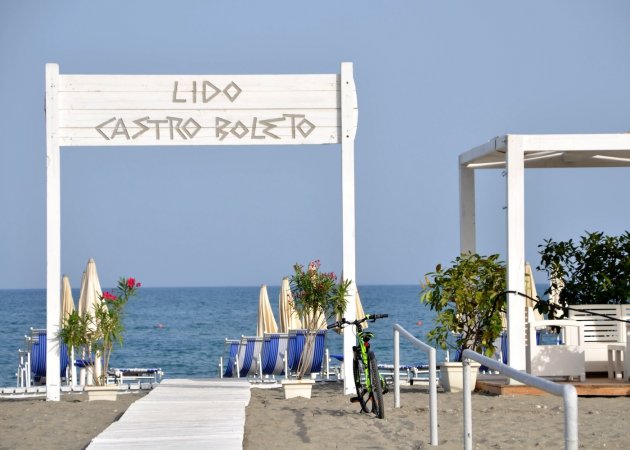 Entrata di un lido sulla spiaggia con mare in lontananza.