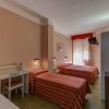Due letti con copriletto a righe rosse in una camera d'albergo con pareti beige.