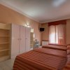 Tre letti con copriletto a righe rosse in una camera d'albergo con mobili bianchi.