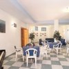 Sala interna con tavoli rotondi, sedie bianche, pianoforte e piante decorative.