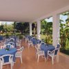 Terrazza coperta con tavoli rotondi, sedie bianche e vista sul giardino.