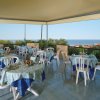 Terrazza con tavoli coperti da tovaglie blu, vista sul mare.