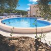 Piscina rotonda all'aperto con persone che nuotano e palme intorno.