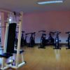 Una palestra con attrezzi e cyclette su pavimento in legno.
