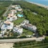 Complesso turistico con piscina e alberi vicino alla spiaggia, visto dall'alto.