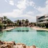 Grande piscina circondata da palme e edifici moderni.