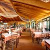 Ristorante con tavoli apparecchiati e soffitto in legno.