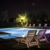 Piscina notturna con sdraio illuminate.