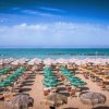 Spiaggia con ombrelloni e sdraio verdi e bianchi.