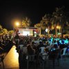 Spettatori in una sala all'aperto assistono a un evento serale.
