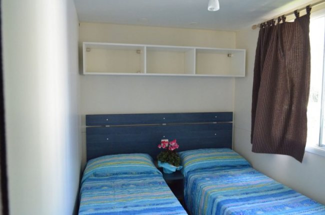 Stanza con due letti singoli e tenda marrone.