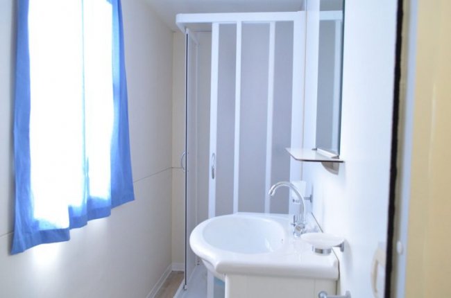 Un bagno con doccia e finestra con tenda blu.