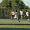 Ragazzi giocano a calcio su un campo all'aperto.