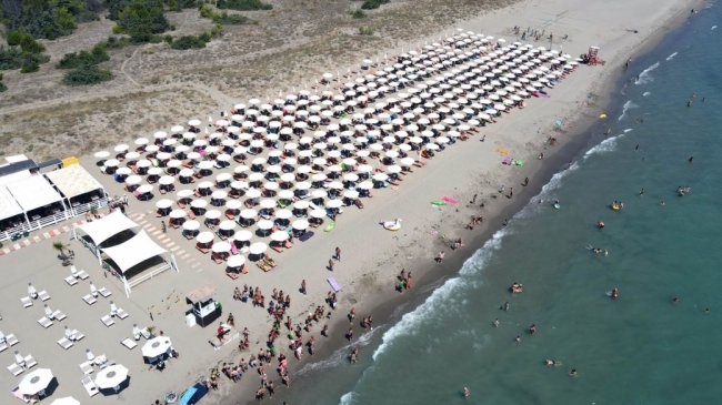 Spiaggia affollata con file di ombrelloni e bagnanti.