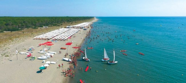 Spiaggia con barche e molte persone in mare.