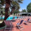 Una piscina con sedie a sdraio e palme circostanti su un patio rosso.