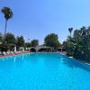Grande piscina all'aperto con lettini e piante tropicali intorno.