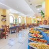 Tavoli da pranzo e buffet con piatti colorati in un ristorante luminoso.