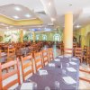 Ristorante spazioso con tavoli apparecchiati e sedie in legno, soffitto moderno.