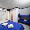 Camera con letto matrimoniale e letto a castello, copriletti blu, porta aperta verso il bagno.