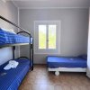 Stanza con letti a castello blu e un letto singolo. Una finestra al centro.