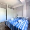 Camera da letto con letto matrimoniale a righe blu, due armadi bianchi e una sedia bianca.