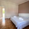 Camera con letto matrimoniale, copriletto a righe blu, parete beige, porta aperta su balcone.