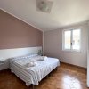 Camera con letto matrimoniale, copriletto a righe blu, finestra luminosa, pavimento marrone.