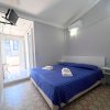 Stanza con letto matrimoniale, copriletto blu, TV a parete e accesso a balcone.