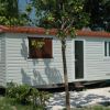 Casa mobile bianca con giardino e sedie verdi.