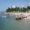 Una spiaggia di ciottoli con acqua limpida, rocce e jet ski.