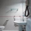 Bagno con piastrelle beige, lavandino e specchio illuminato.