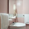 Bagno rosa con asciugacapelli e lavandino.