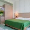 Camera con letto verde e fiori su una scrivania.