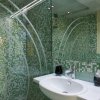 Bagno moderno con piastrelle verdi e doccia in vetro.