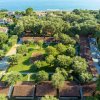 Vista aerea di un parco verde con alberi e costruzioni, vicino al mare.