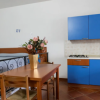 Monolocale con letto, cucina blu e tavolo con fiori.