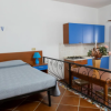 Monolocale con letto matrimoniale, cucina blu e tavolo.