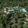 Una veduta aerea di un complesso immerso nel verde con un campo sportivo e una piscina.